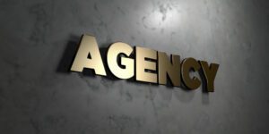 Gold agency sign mounted on a dark marble wall