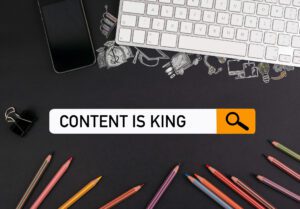 content is king concept. On a black table colorful pencils and a computer keyboard with a mobile phone.