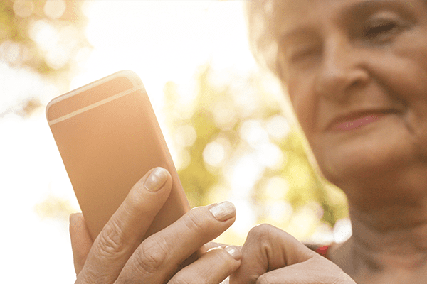 older woman using a cellphone in the sunlight