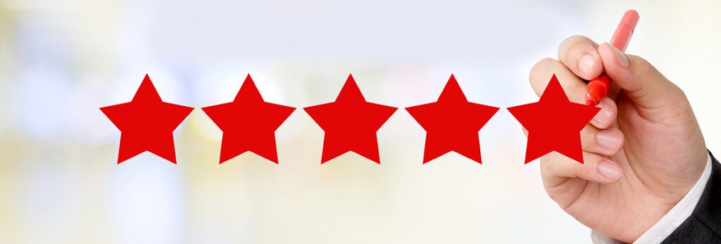 A hand holding a red marker draws the fifth star in a row of five large red stars, symbolizing a five-star rating on a blurred light background.