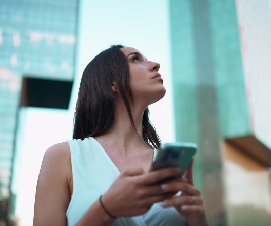 woman holding phone looking at buildings