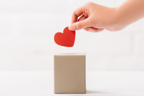 hand placing paper heart into box