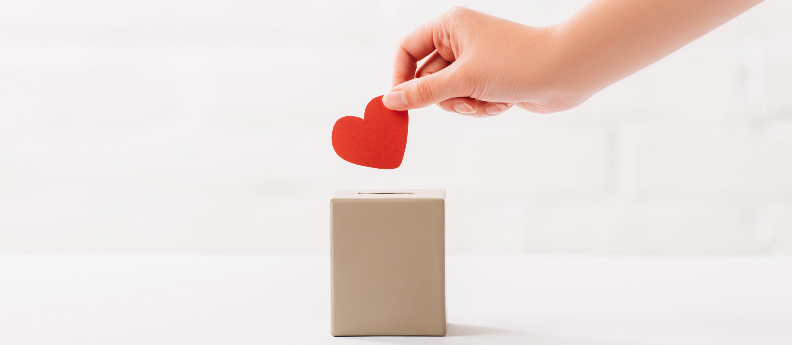 hand placing paper heart into box