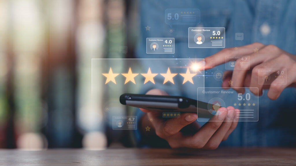A person uses a smartphone, tapping a digital display with five gold stars, representing a high rating—demonstrating how to use Google reviews. Floating icons show customer reviews and ratings in the background.